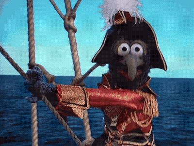 A Muppet Wearing A Pirate Costume Is Standing On A Boat GIF