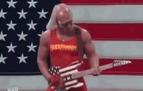 A Muscular Man Is Playing A Guitar In Front Of An American Flag . GIF