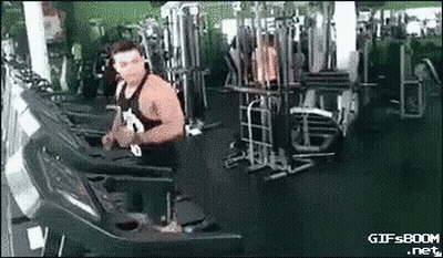 A Muscular Man Is Running On A Treadmill In A Gym . GIF
