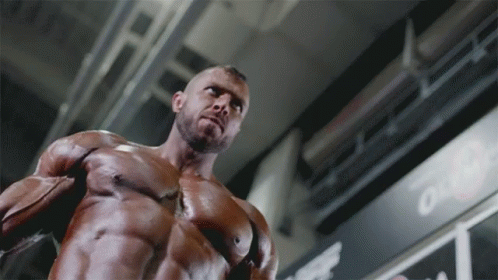 A Muscular Man Is Standing In Front Of A Sign That Says " Out " GIF