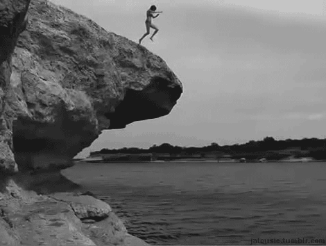 A Naked Man Is Jumping Off A Cliff Into The Water . GIF