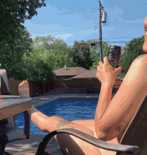 A Naked Man Is Sitting In A Chair Holding A Can Of Coke GIF