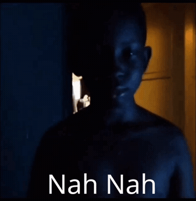 A Naked Man Is Standing In A Dark Room With The Words `` Nah Nah '' Written On The Bottom . GIF