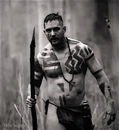 A Naked Man With Tattoos On His Body Is Holding A Spear . GIF