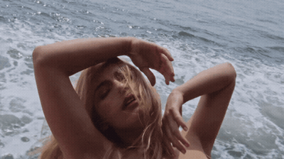 A Naked Woman Is Laying In The Water With Her Hands On Her Head GIF