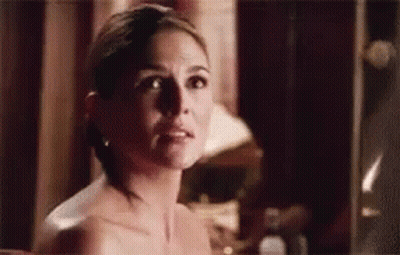 A Naked Woman Is Standing In Front Of A Mirror Looking At Herself . GIF