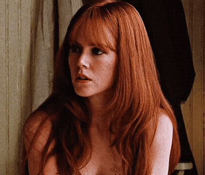 A Naked Woman With Long Red Hair And Freckles Is Looking At The Camera GIF