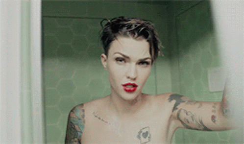 A Naked Woman With Tattoos On Her Arms And Chest Is Taking A Selfie GIF