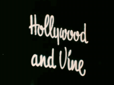 A Neon Sign For The Hollywood Theater Is Lit Up At Night GIF