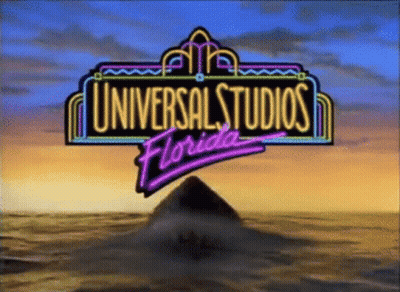 A Neon Sign For Universal Studios Florida With A Pyramid In The Background GIF