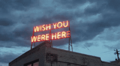A Neon Sign On Top Of A Building Says " Wish You Were Here " GIF
