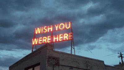 A Neon Sign On Top Of A Building Says " Wish You Were Here " GIF
