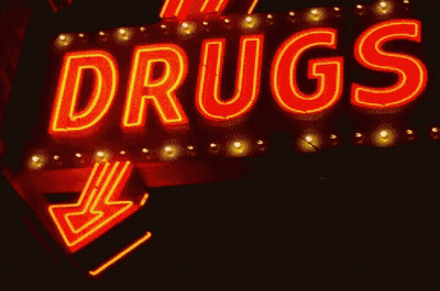 A Neon Sign That Says " Drugs " With An Arrow Pointing To The Right GIF