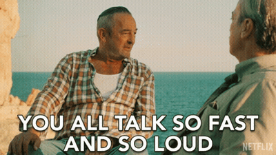 A Netflix Ad Shows Two Men Sitting On A Rock Near The Ocean And Says " You All Talk So Fast And So Loud " GIF