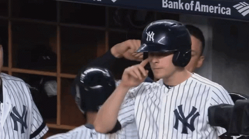 A New York Yankees Player Adjusts His Helmet In Front Of A Bank Of America Banner GIF