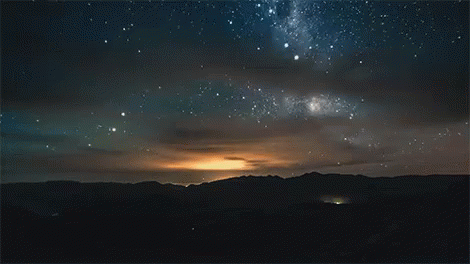 A Night Sky With A Lot Of Stars And Mountains In The Background GIF