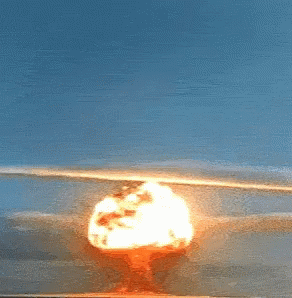 A Nuclear Explosion Is Visible In The Distance With A Blue Sky In The Background GIF