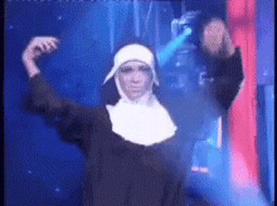 A Nun Is Dancing In A Dark Room With A Blue Light Behind Her . GIF