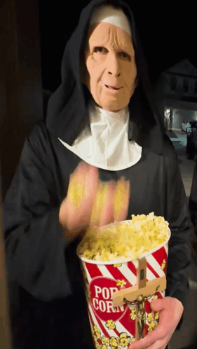 A Nun Is Holding A Bucket Of Popcorn GIF