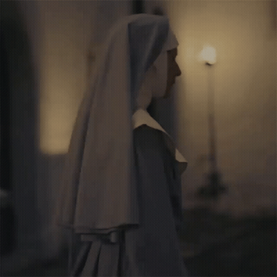 A Nun Is Standing In A Dark Room Wearing A White Veil GIF