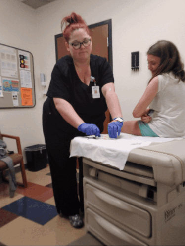 A Nurse Is Working On A Child 'S Leg In A Room That Has A Box That Says Rite GIF