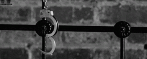 A Pair Of Handcuffs Hanging From A Metal Railing . GIF