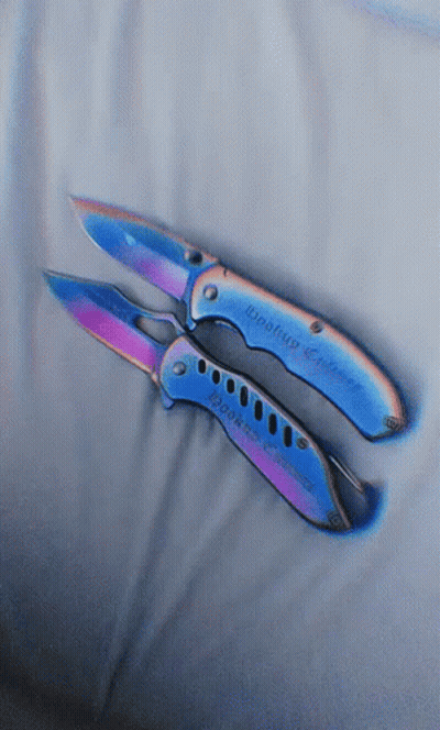 A Pair Of Knives With A Rainbow Colored Handle Are Laying On A White Cloth GIF
