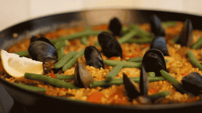 A Pan Filled With Rice Mussels Green Beans And Lemon Slices GIF