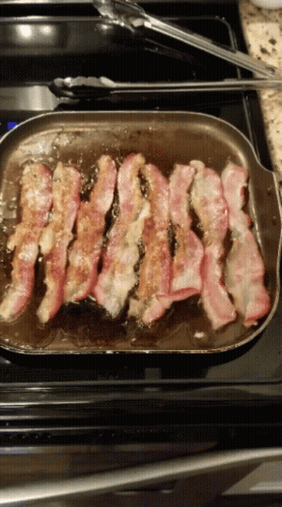 A Pan Of Bacon Is Being Cooked On A Stove Top GIF