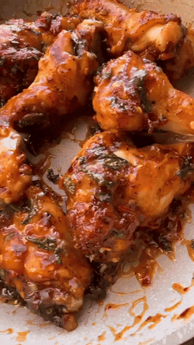 A Pan Of Chicken Wings With Sauce On Them GIF