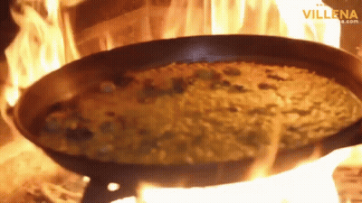 A Pan Of Food Is Being Cooked On A Fire With The Website Villena.com Visible In The Corner GIF