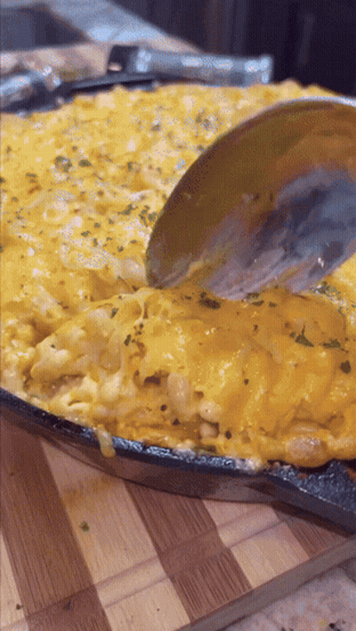 A Pan Of Macaroni And Cheese With A Spoon In It GIF