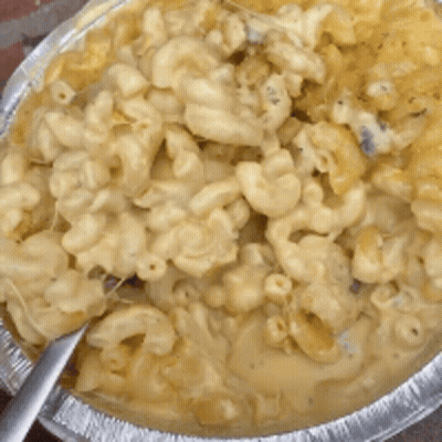 A Pan Of Macaroni And Cheese With A Spoon In It GIF