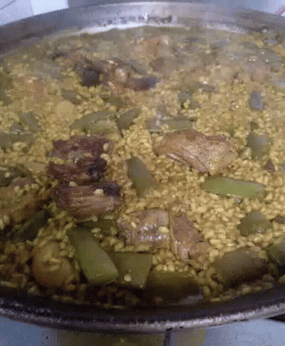 A Pan Of Rice With Meat And Vegetables Is Being Cooked GIF
