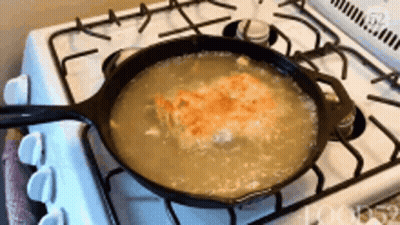 A Pan Of Soup Is Cooking On A Stove Top GIF