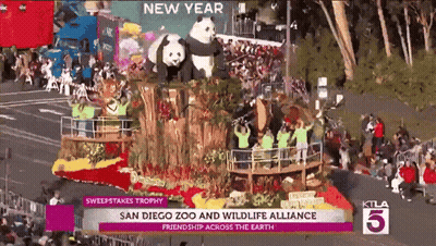 A Parade With A Float That Says ' San Diego Zoo And Wildlife Alliance Friendship Across The Earth ' On It GIF