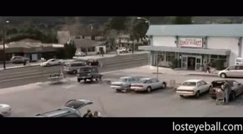 A Parking Lot With Cars Parked In Front Of A Ranch Market GIF
