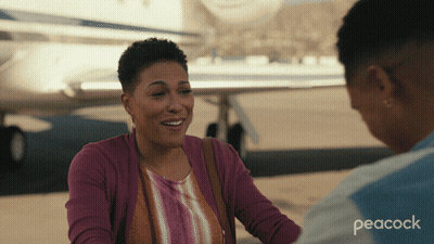 A Peacock Ad Shows Two Women Talking In Front Of A Plane GIF