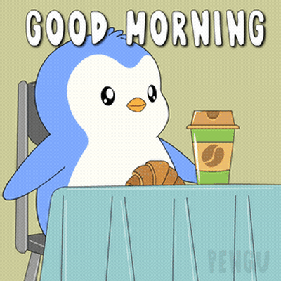 A Penguin Is Sitting At A Table With A Cup Of Coffee And A Croissant GIF