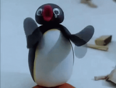 A Penguin Made Out Of Clay Is Standing On Top Of A Piece Of Wood . GIF