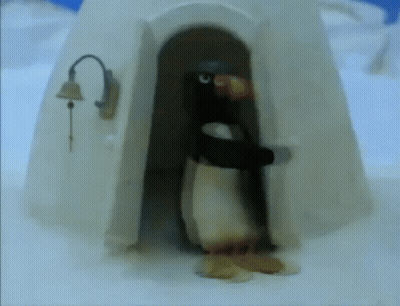 A Penguin Standing In Front Of An Igloo With A Bell On It GIF