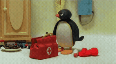 A Penguin Standing Next To A Red Bag With A White Cross On It GIF
