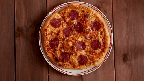 A Pepperoni Pizza Is Sitting On A White Plate GIF