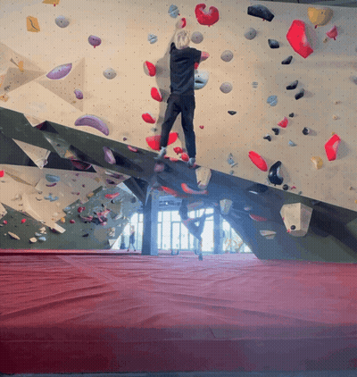 A Person Climbs A Climbing Wall With A Red Mat GIF
