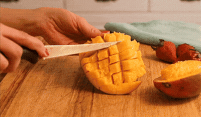 A Person Cutting A Mango On A Cutting Board GIF