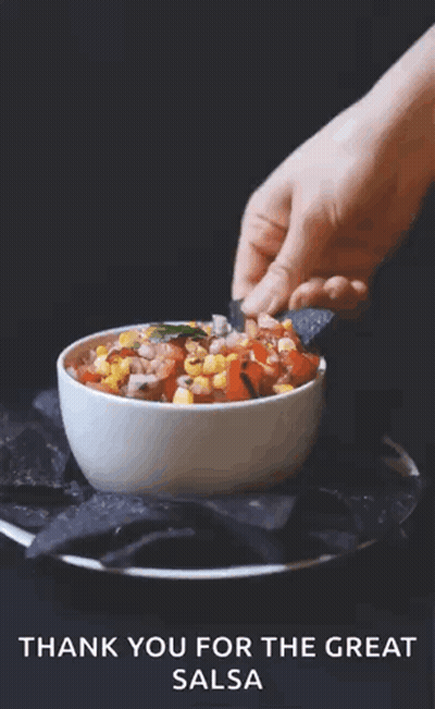 A Person Dipping A Chip Into A Bowl Of Salsa GIF