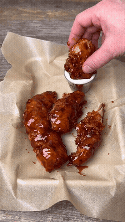 A Person Dipping A Piece Of Chicken Into A Sauce GIF