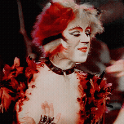 A Person Dressed As A Cat With Red Hair GIF