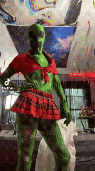 A Person Dressed As A Creeper In A Red And Green Outfit GIF