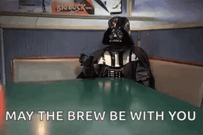 A Person Dressed As Darth Vader Is Sitting At A Table In A Diner And Saying `` May The Brew Be With You '' GIF